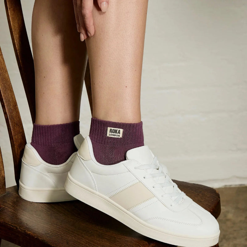 White sneakers with purple socks on a wooden chair