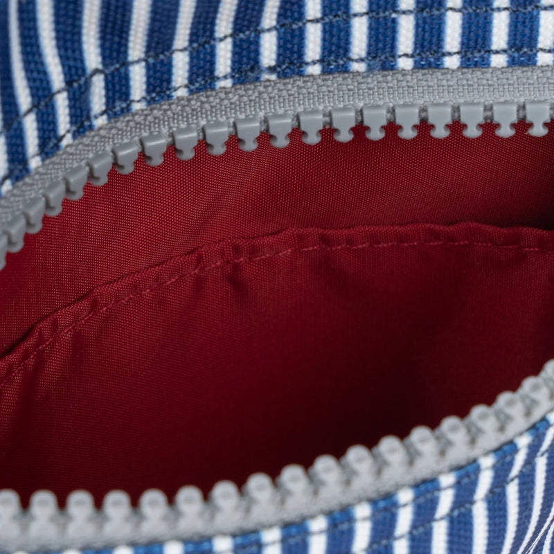 Close-up of a zipper on a red and blue striped fabric bag.