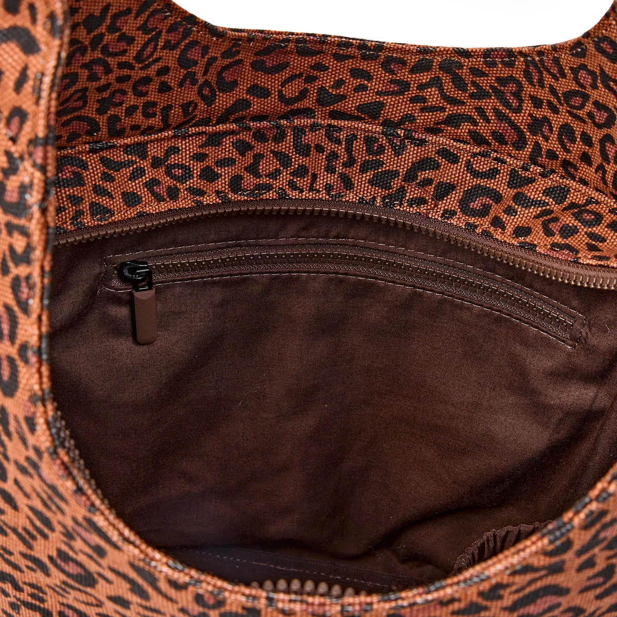 Close-up of the interior of a leopard-print bag, showing a brown suede-like lining with a zippered pocket and a brown and black animal pattern on the fabric.
