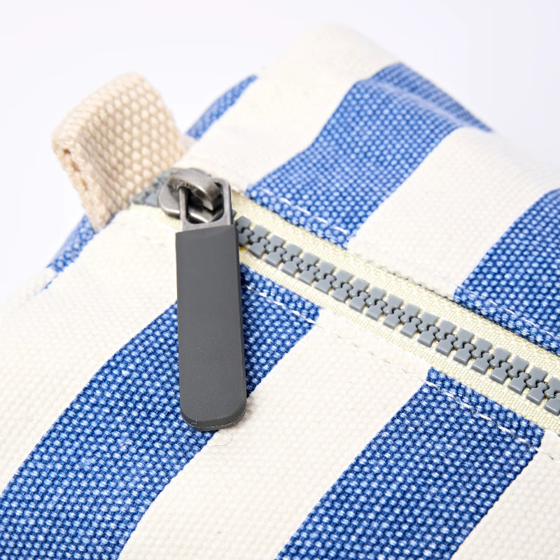 Close-up of a gray zipper on a blue and white striped fabric bag.
