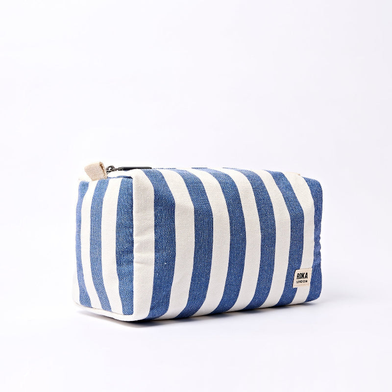 Roka Mayfair Wash Bag Denim Stripe Blue and white pouch on a light gray background