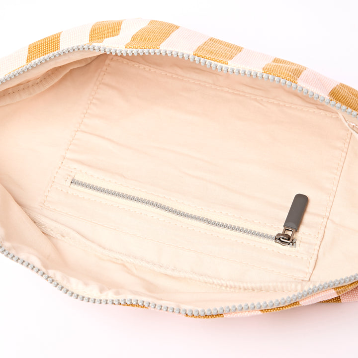 Close-up of a beige pouch with a zipper and yellow striped pattern on a white background