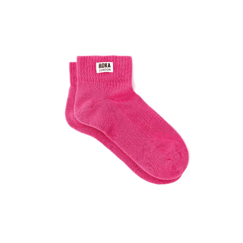 Pink sock with 'Roka London' label on a white background