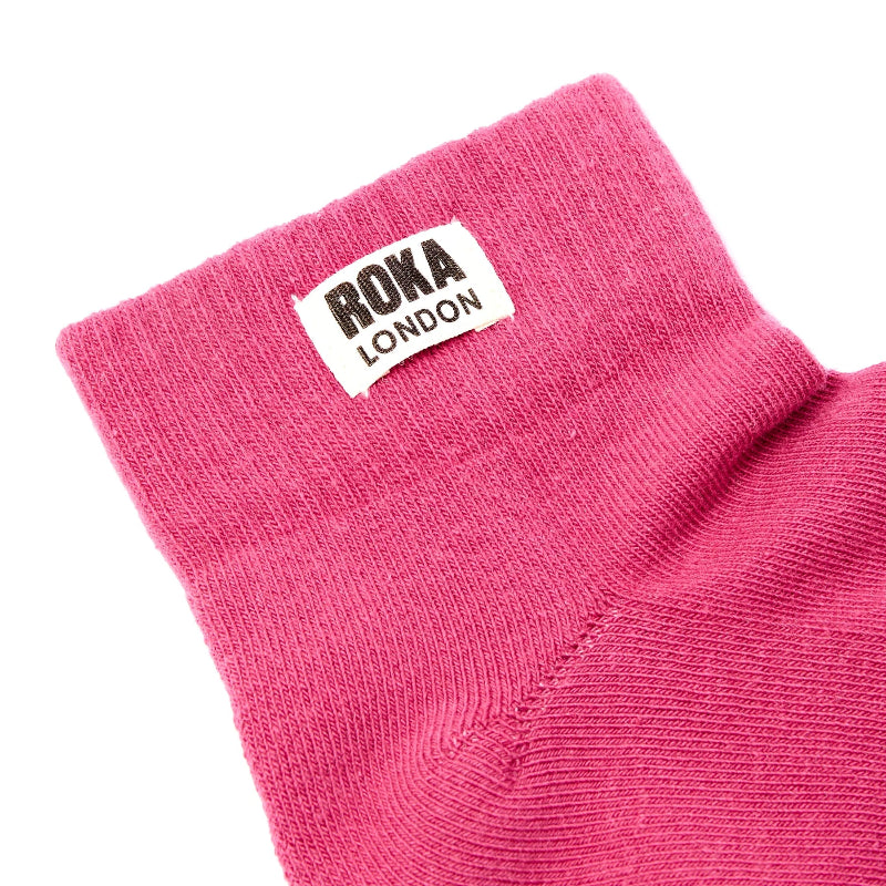 Close-up of a pink sock with a Roka London label on a white background
