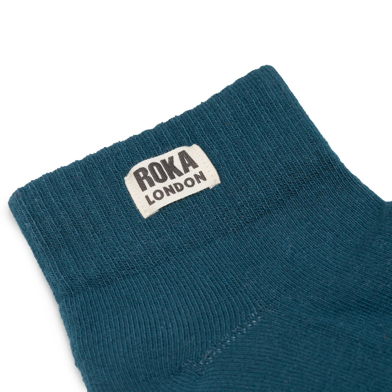 Teal sock with Roka London label on a white background