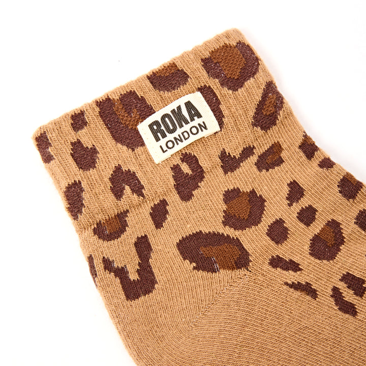 Brown sock with leopard print pattern and Roka London label on a white background