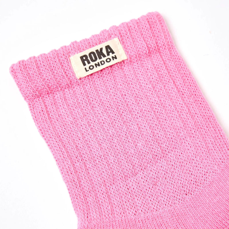 Pink sock with Roka London label on a white background