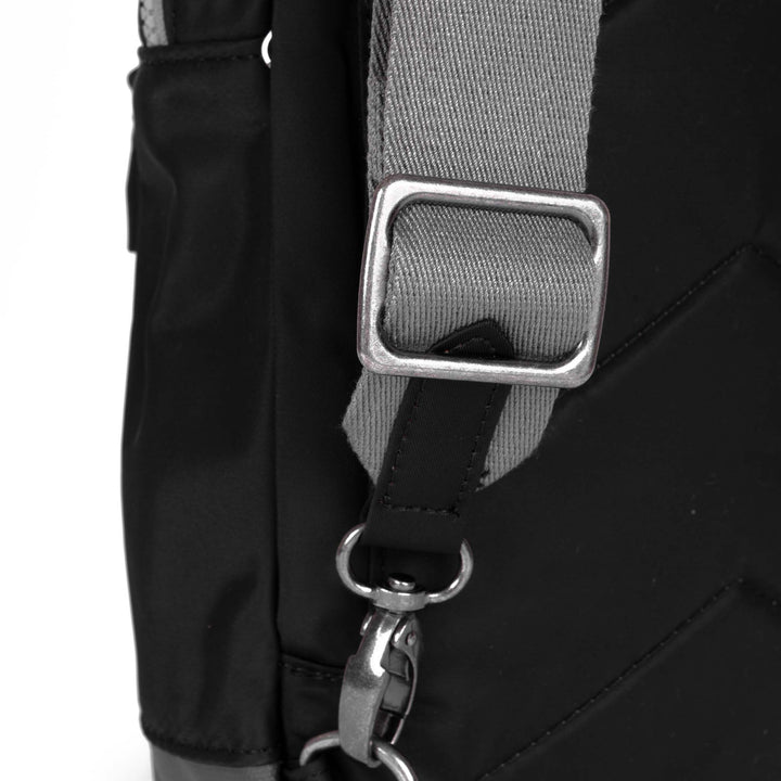 Close-up of a black bag with a gray strap and silver buckle on a white background
