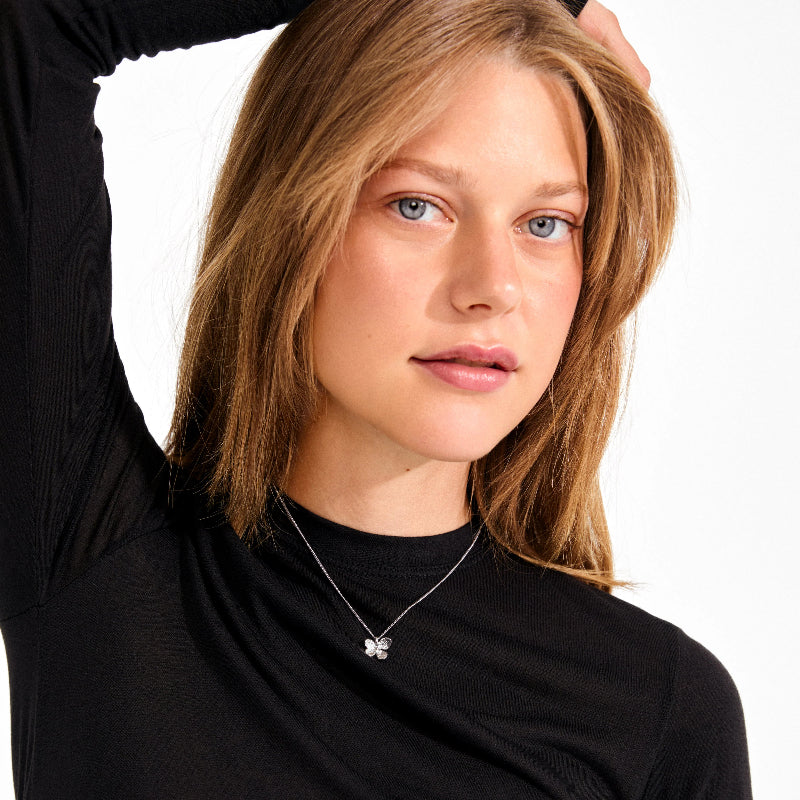 A woman wearing a silver flower necklace on a black top