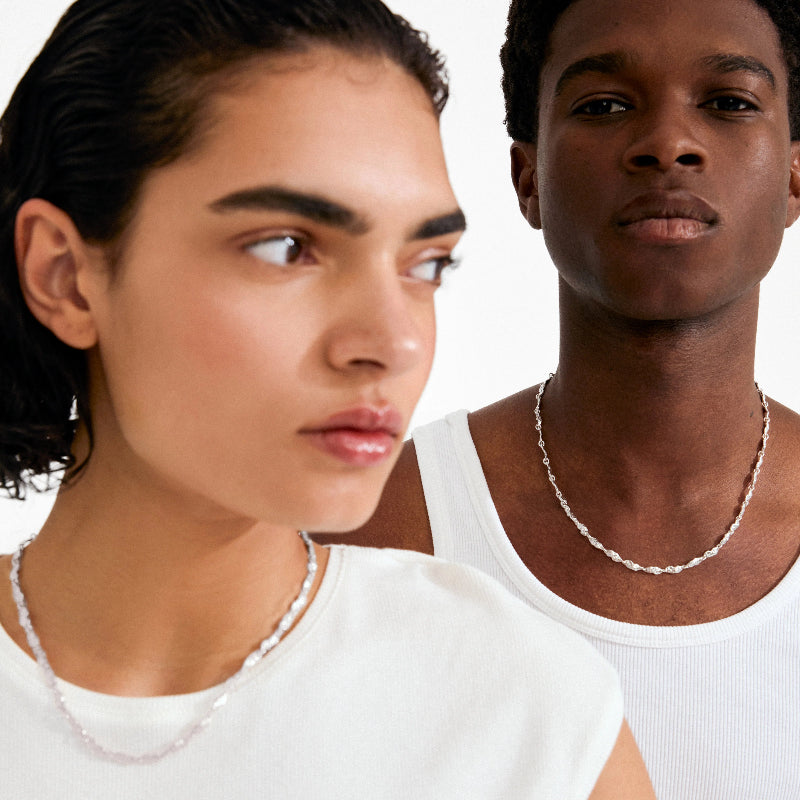 Two people wearing a silver necklace on a white background