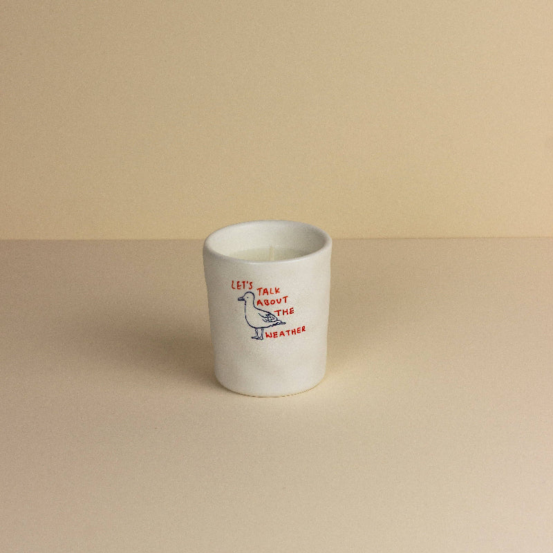 White ceramic cup with red text and a design on a beige background