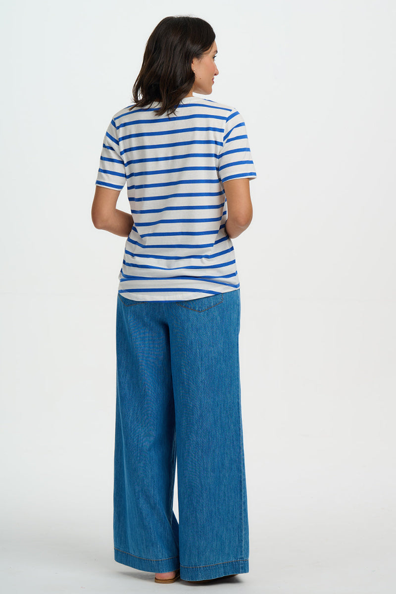 Person wearing a blue and white striped shirt and blue jeans on a white background