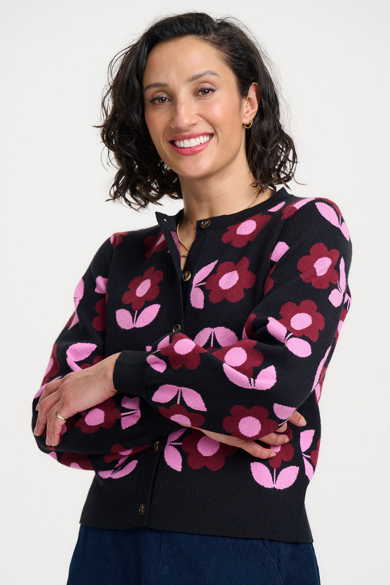 Woman wearing a black cardigan with pink floral patterns on a white background