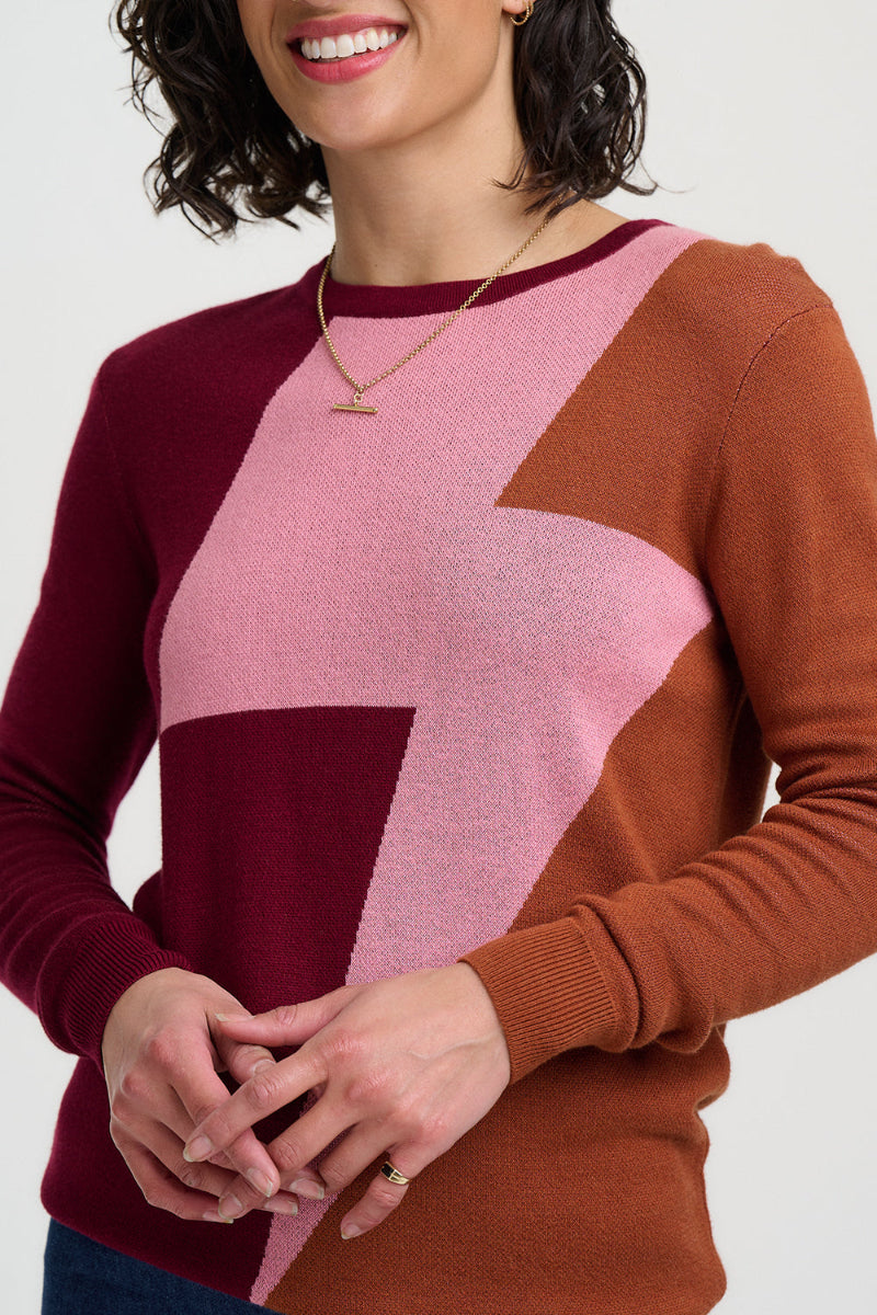 Woman wearing a sweater with a geometric color-block design on a plain background