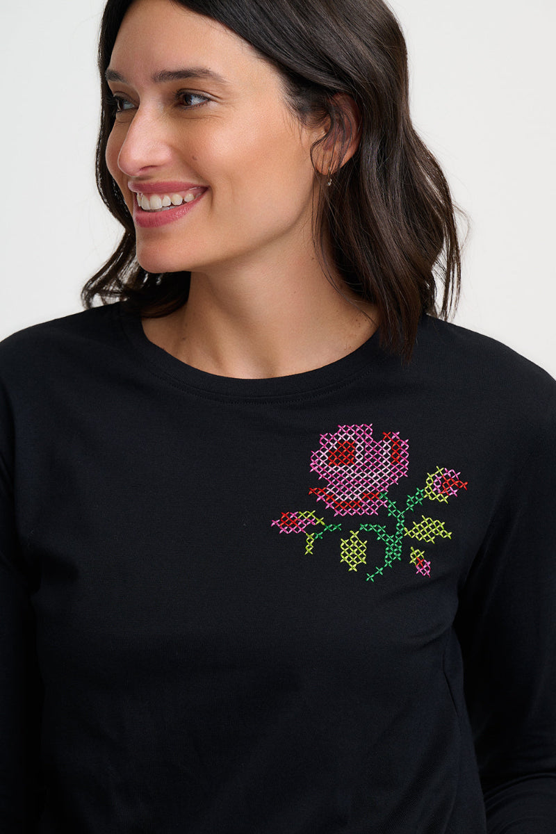 Woman wearing a black sweater with a colorful floral design on a white background