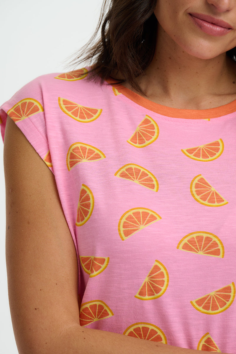 Pink t-shirt with orange slice pattern worn by a person