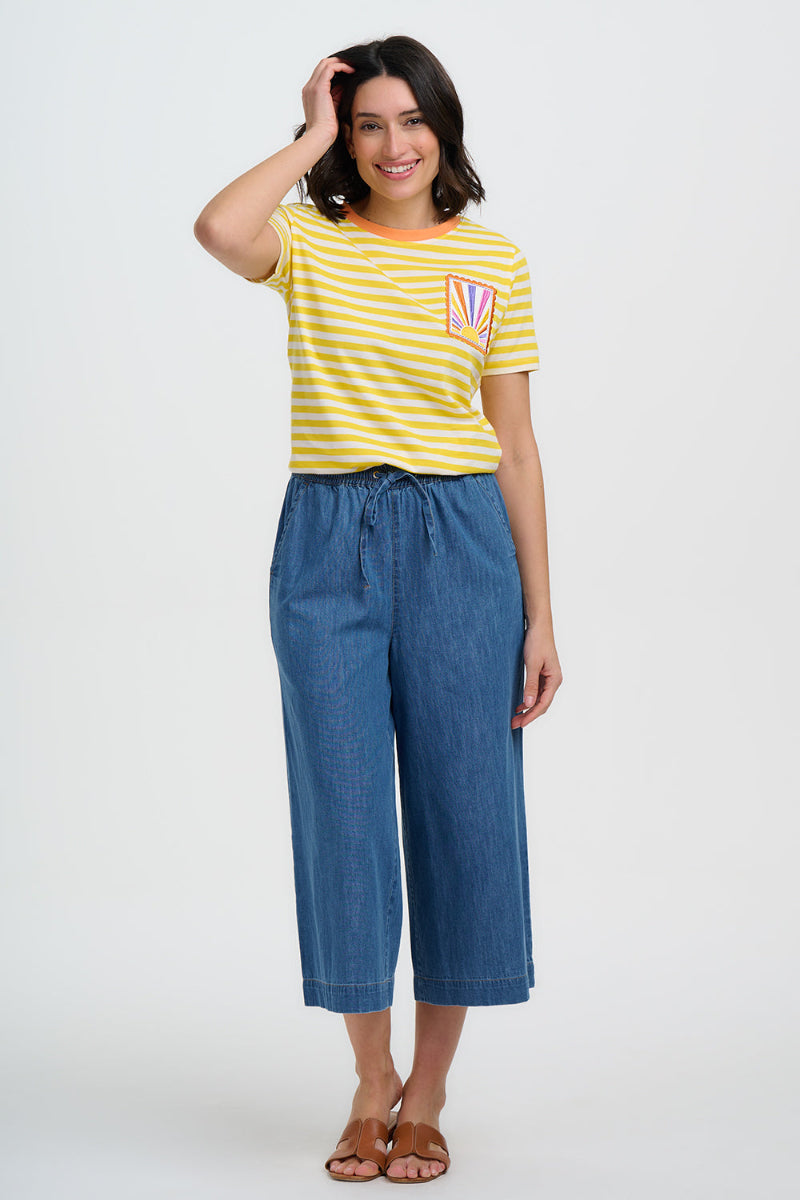 Woman wearing a yellow striped shirt and blue jeans on a white background