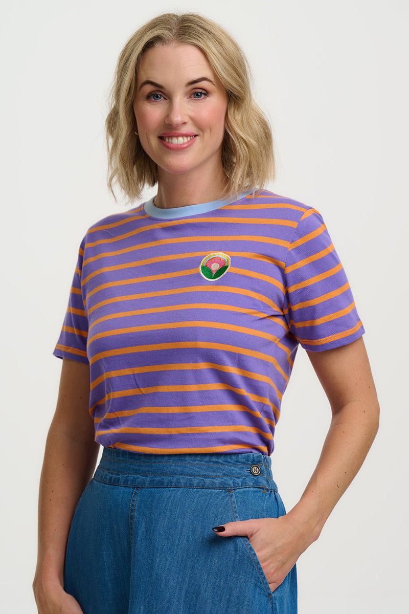 Woman wearing a purple and orange striped shirt with a logo on a white background