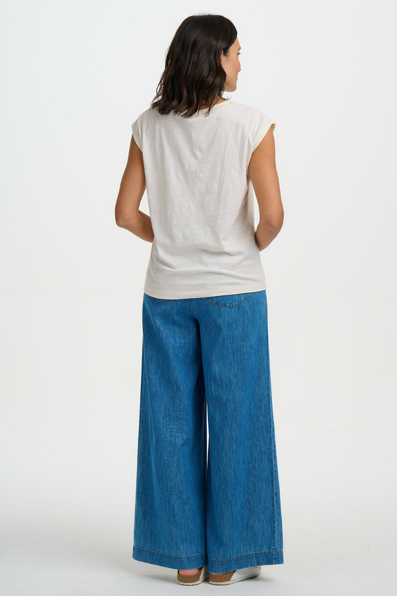 Woman wearing a white sleeveless top and blue jeans on a white background