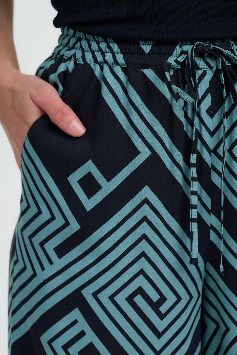 Black pants with blue geometric pattern worn by a person.