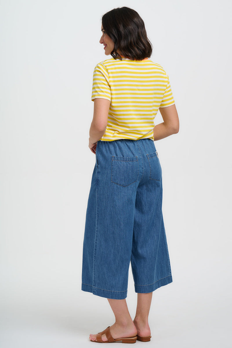 Woman wearing a yellow striped shirt and blue denim pants on a white background