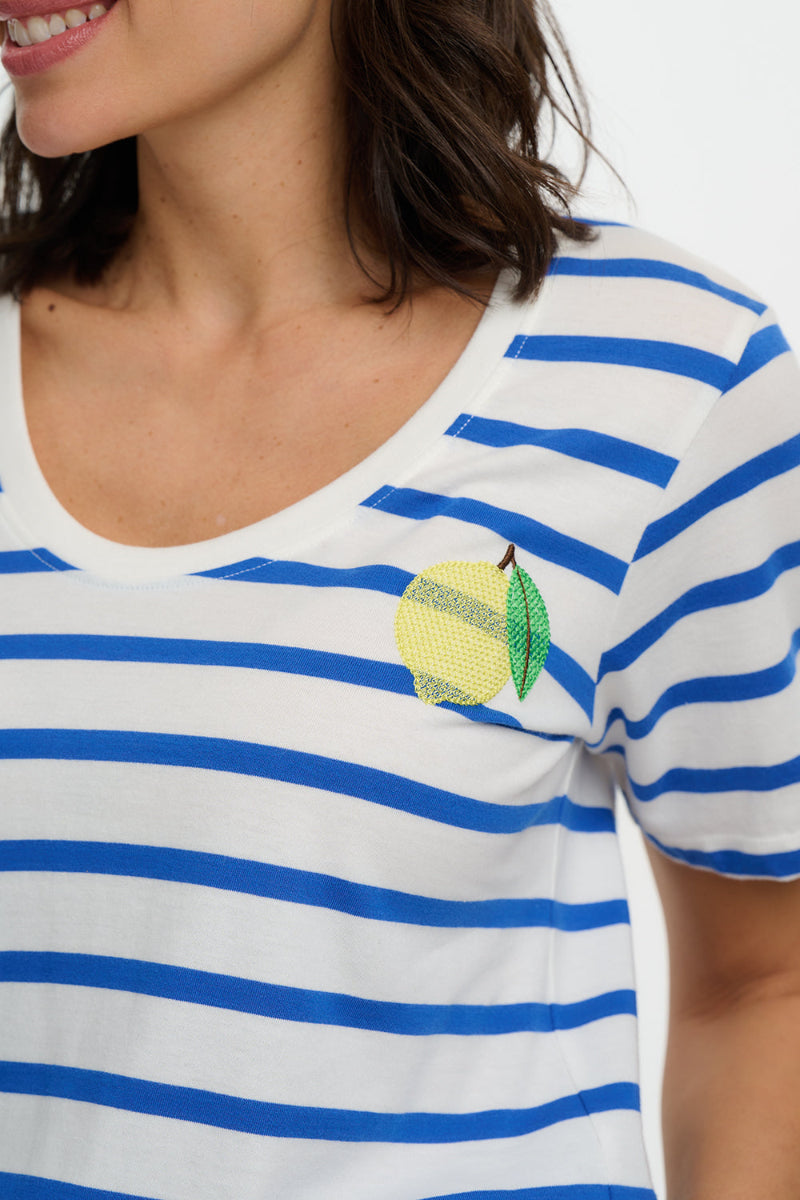 Woman wearing a white and blue striped shirt with a lemon design on a plain background