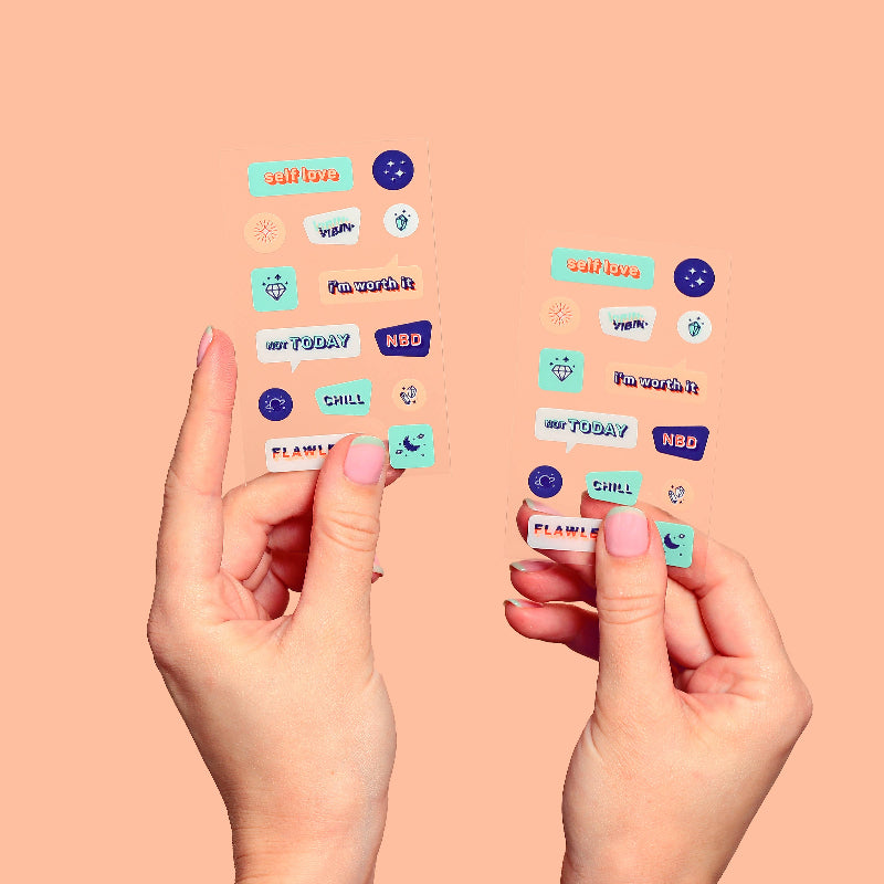 Colorful text stickers on a peach background with hands holding them.