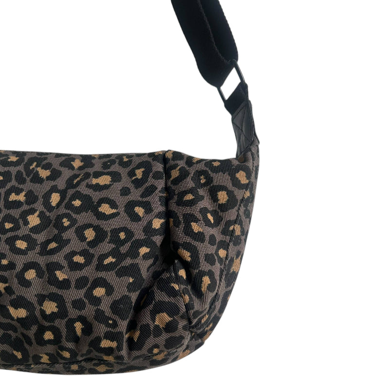 Close-up of a shoulder bag with a dark leopard print pattern in black and tan, featuring a black strap against a white background.