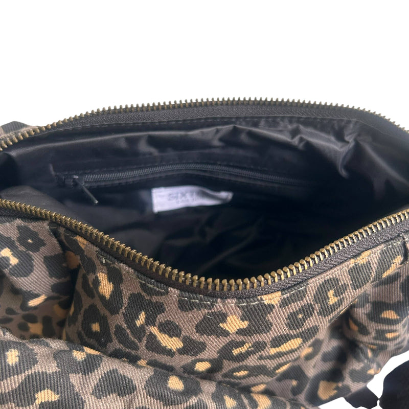 Close-up of an open bag showing a leopard print exterior in black and tan, with a black interior and a visible SIXTEEN brand label inside.