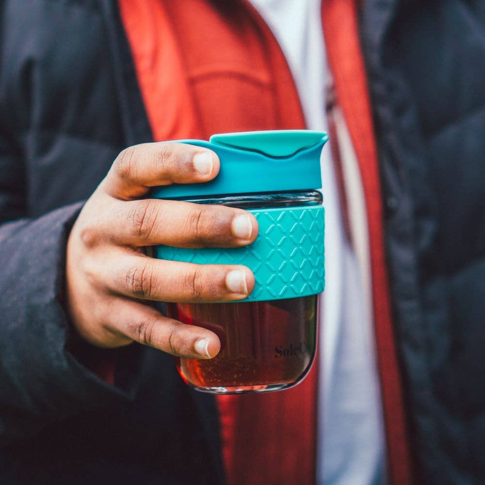 Person holding a blue insulated mug outdoors