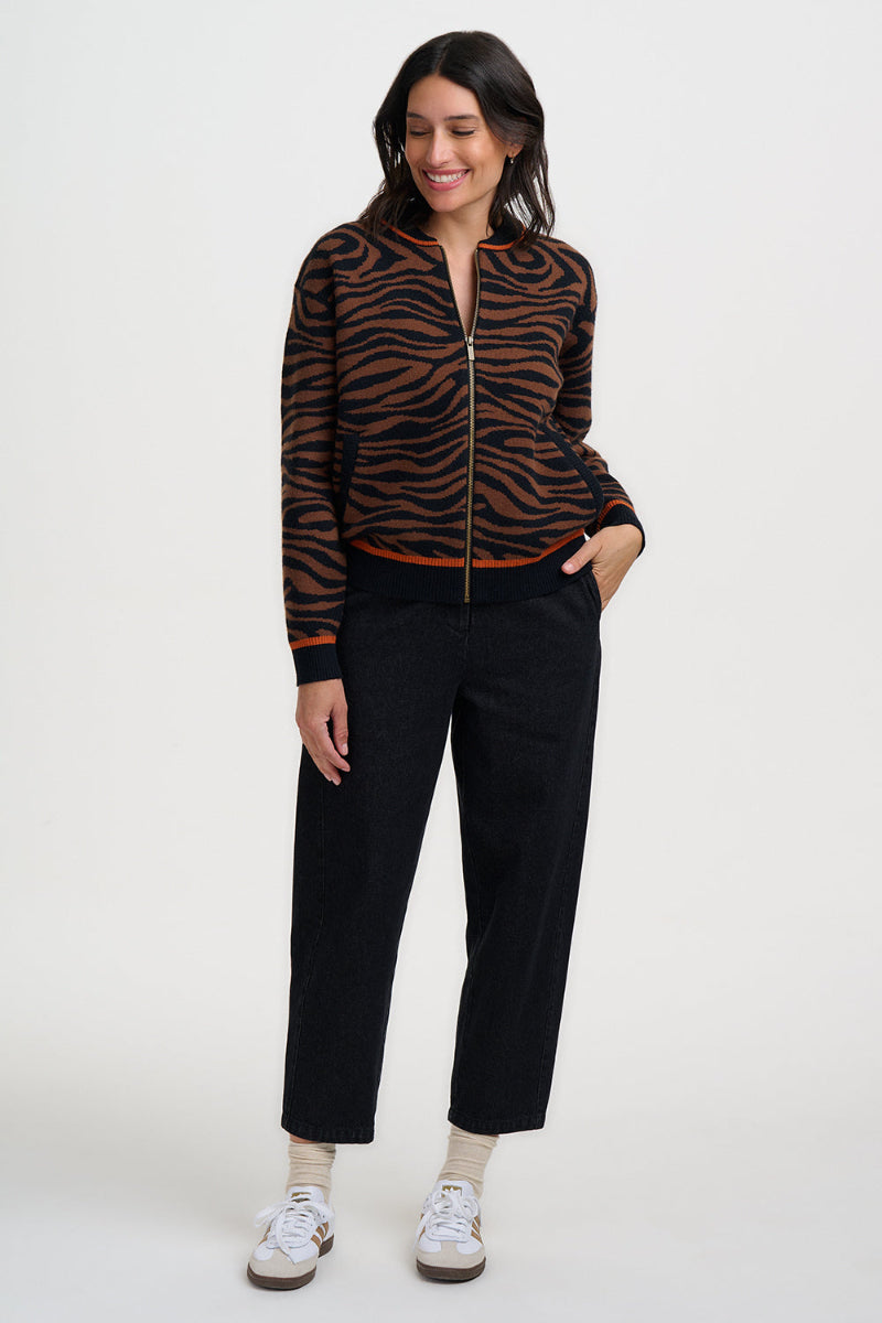 Woman wearing a zebra print jacket and black pants on a white background