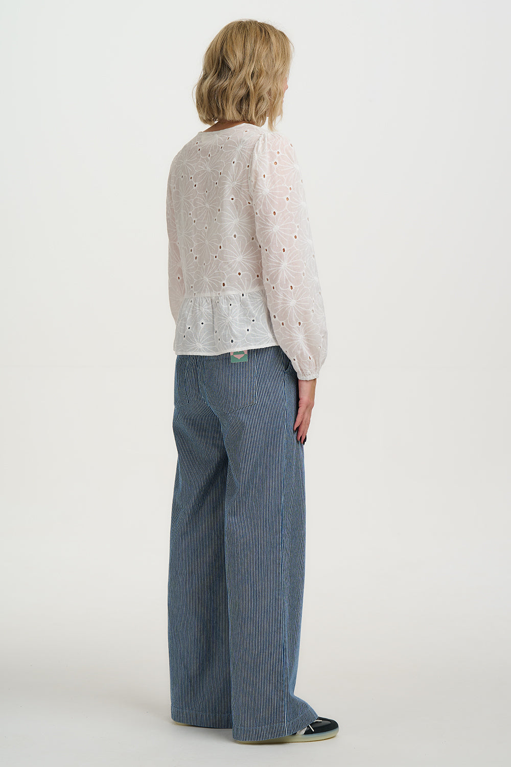 Person wearing a Sugarhill Broderie Anglaise Morgan Top and blue pants on a white background