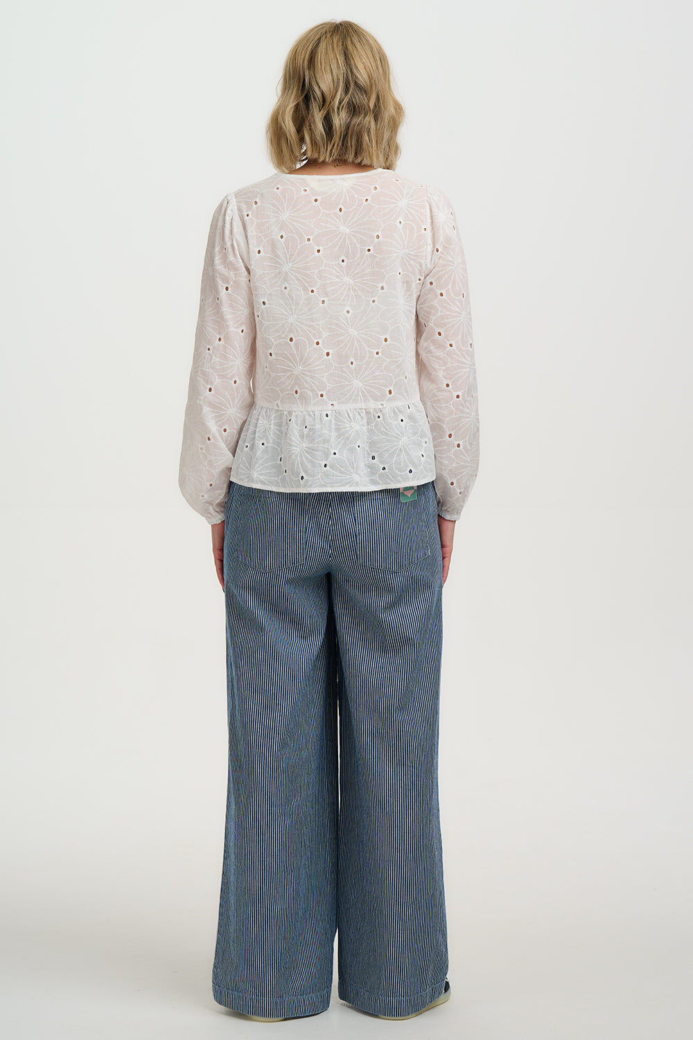 Person wearing a Sugarhill Broderie Anglaise Morgan Top with floral embroidery and blue jeans on a white background