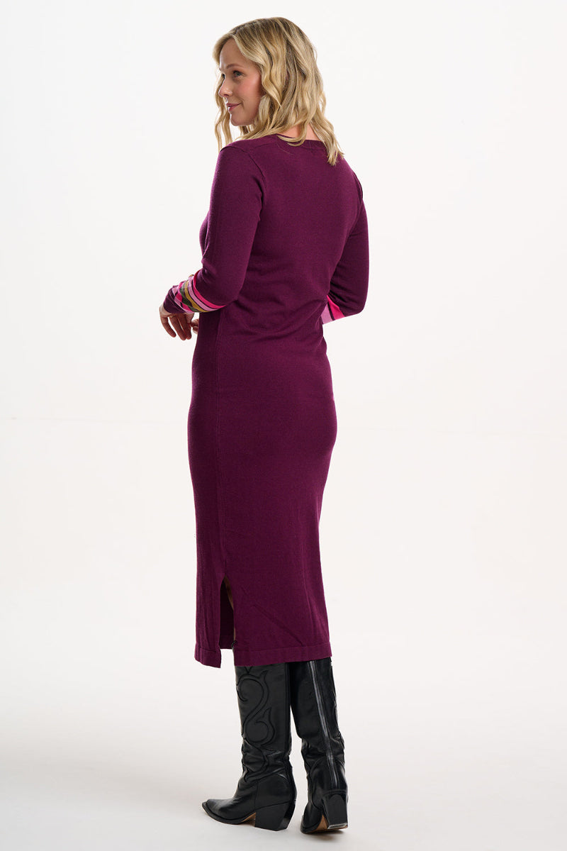Woman wearing a long purple dress with black boots on a white background