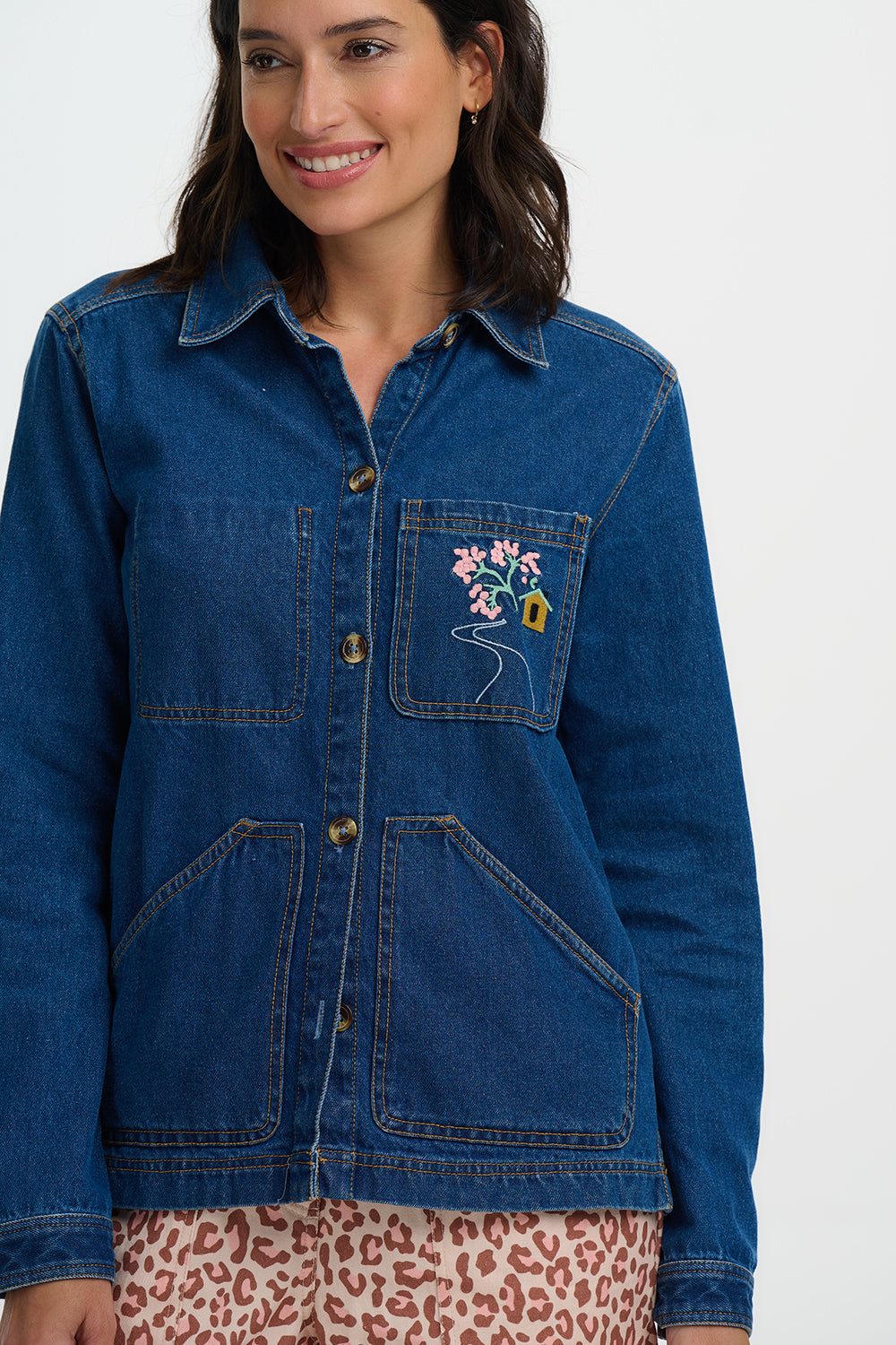 Woman wearing a Sugarhill Dita Denim Jacketwith floral embroidery on a white background