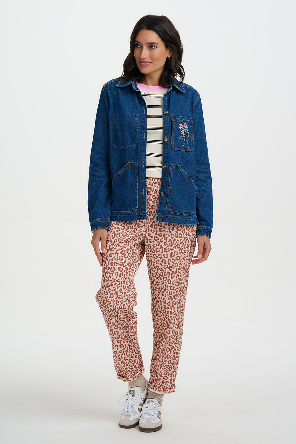 Woman wearing a Sugarhill Dita Denim Jacket, and pink leopard print pants on a white background