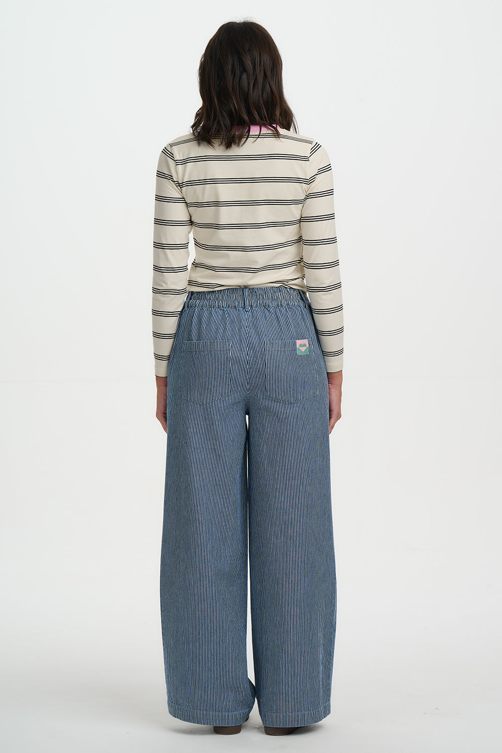 Person wearing a striped shirt and blue wide-leg pants on a white background