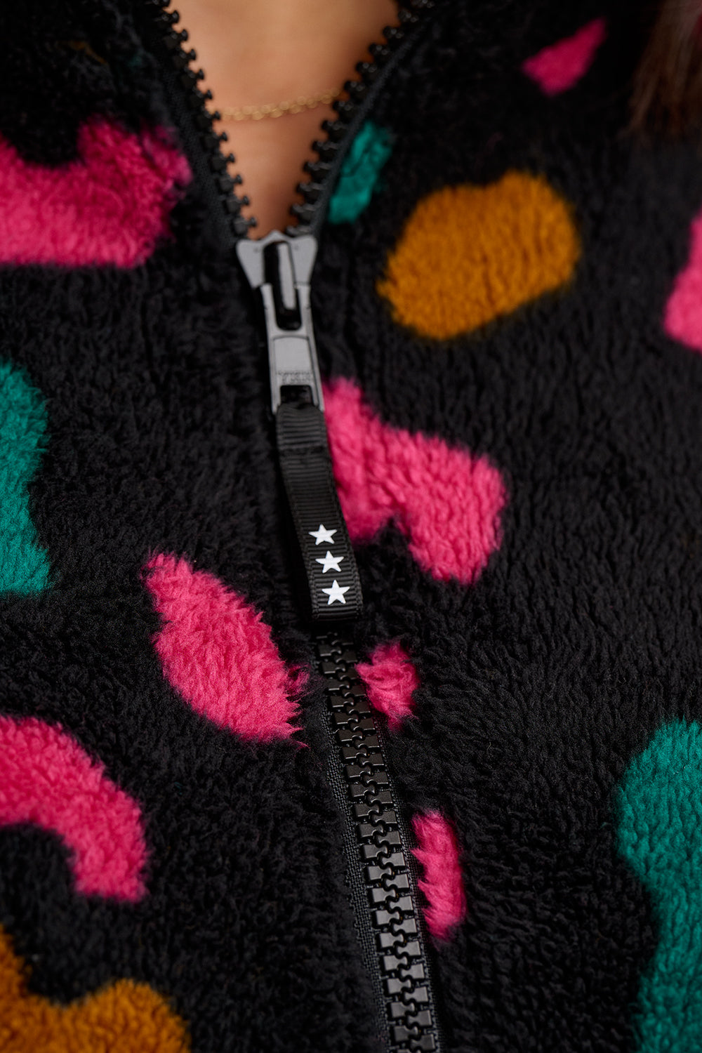 Close-up of a black zip-up fleece with colorful abstract patterns