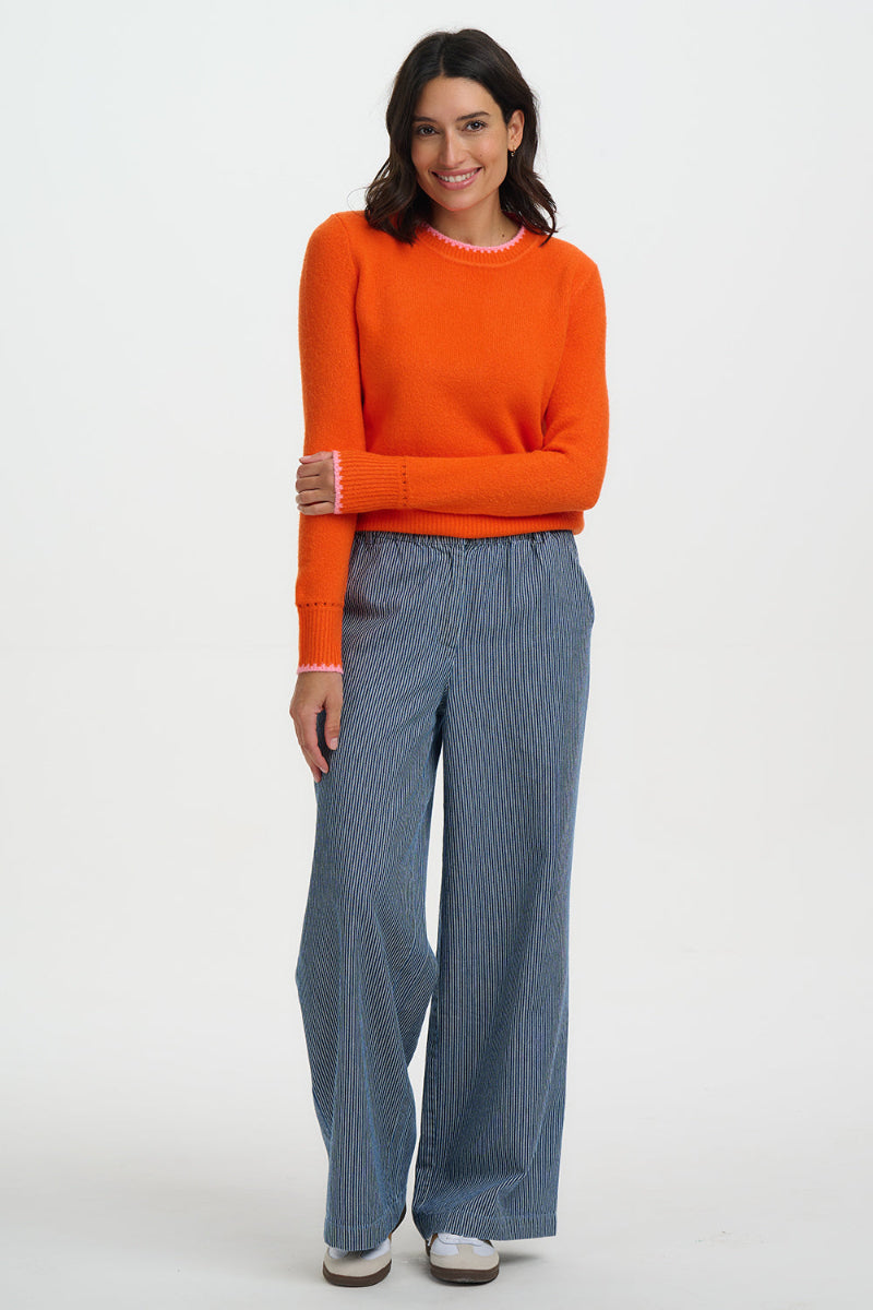 Woman wearing an Sugarhill Helena Jumper-Orange/Pink Tippingand blue pants on a white background