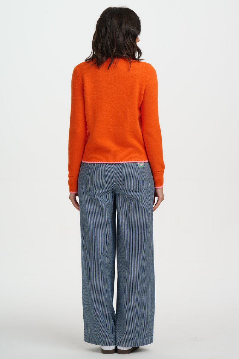 Person wearing an Sugarhill Helena Jumper-Orange/Pink Tipping and blue jeans on a white background