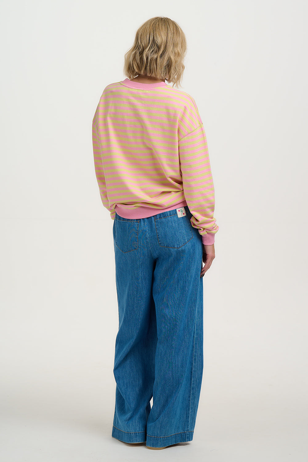 Person wearing a striped shirt and blue jeans on a white background