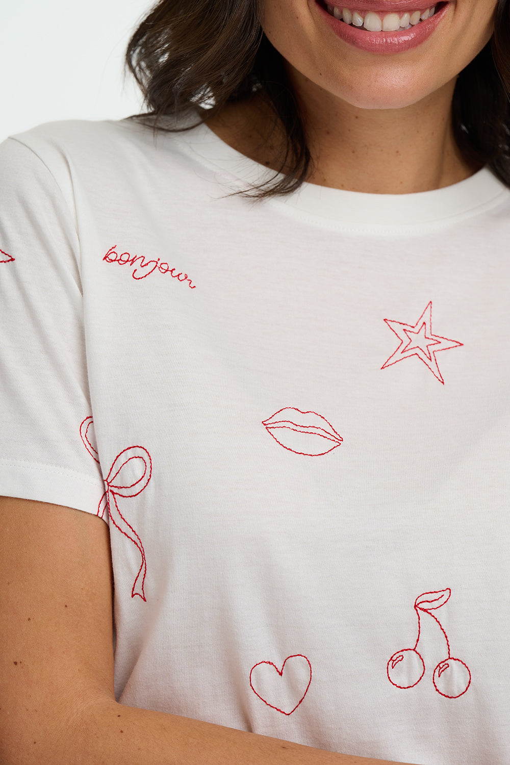 White t-shirt with red embroidered designs on a person wearing it.