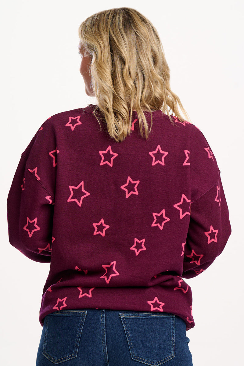 Person wearing a maroon sweater with pink star patterns on a white background