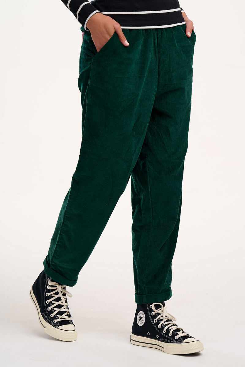 Person wearing Sugarhill Vonnie Trouser Green cords and black Converse shoes on a white background