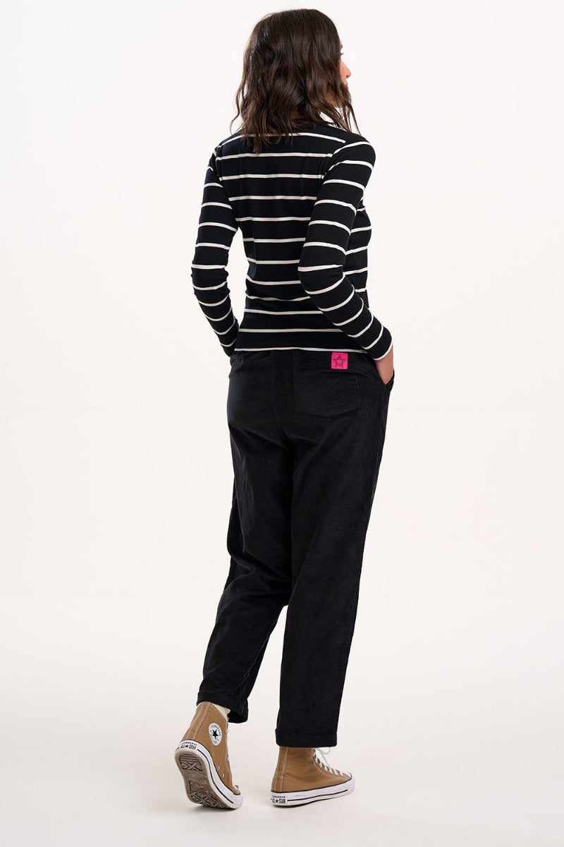 Person wearing a black and white striped shirt and black pants on a white background