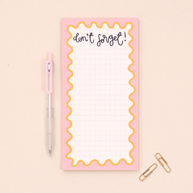 Notepad with 'don't forget!' text on a pink background, accompanied by a pen and paper clip.