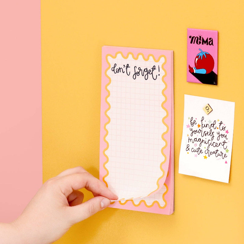 Hand holding a pink notepad with 'don't forget!' text on a yellow background