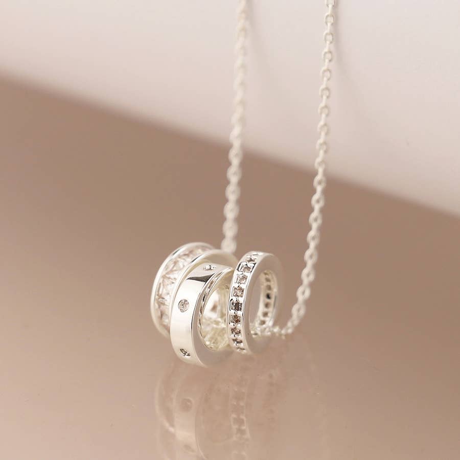 Silver necklace with interlocking rings on a beige background