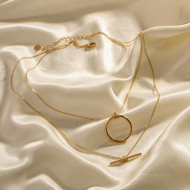 Gold necklace with a circular pendant on a beige fabric background