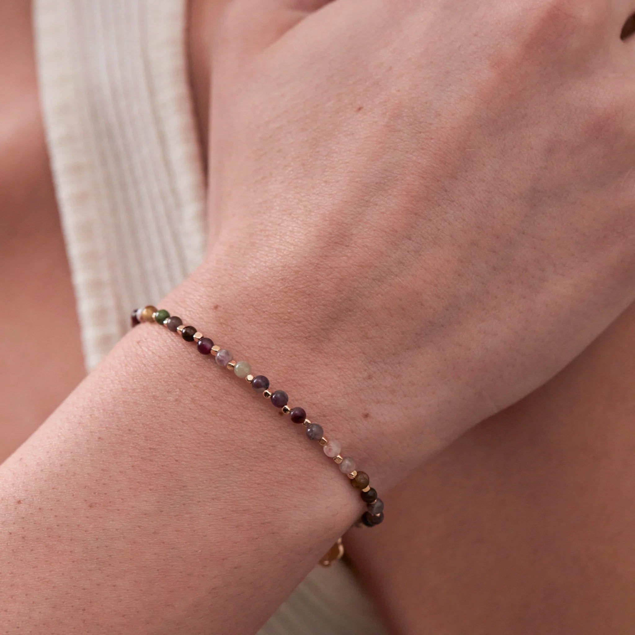 Close-up of a wrist wearing a beaded bracelet with a neutral background
